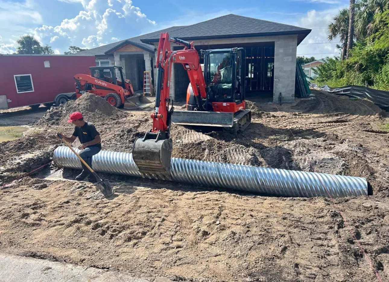 Construction site with excavator and metal pipe.