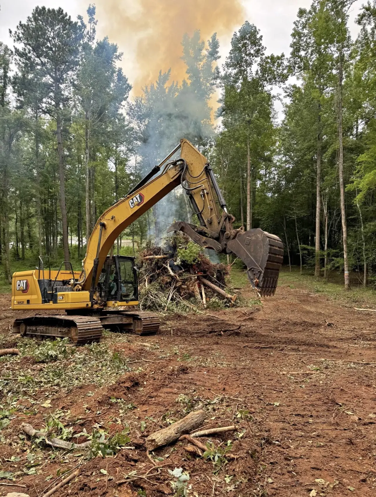 Excavator clearing land in a forested area.