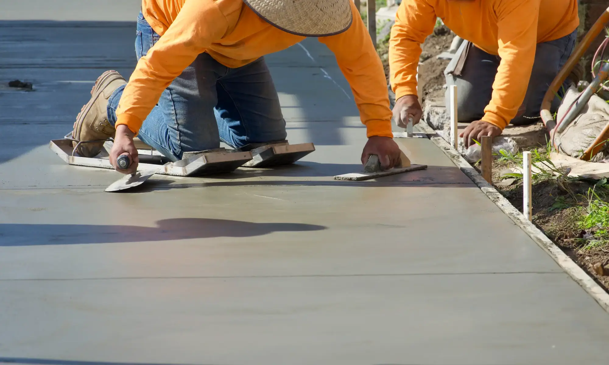 Workers smoothing freshly poured concrete surface.