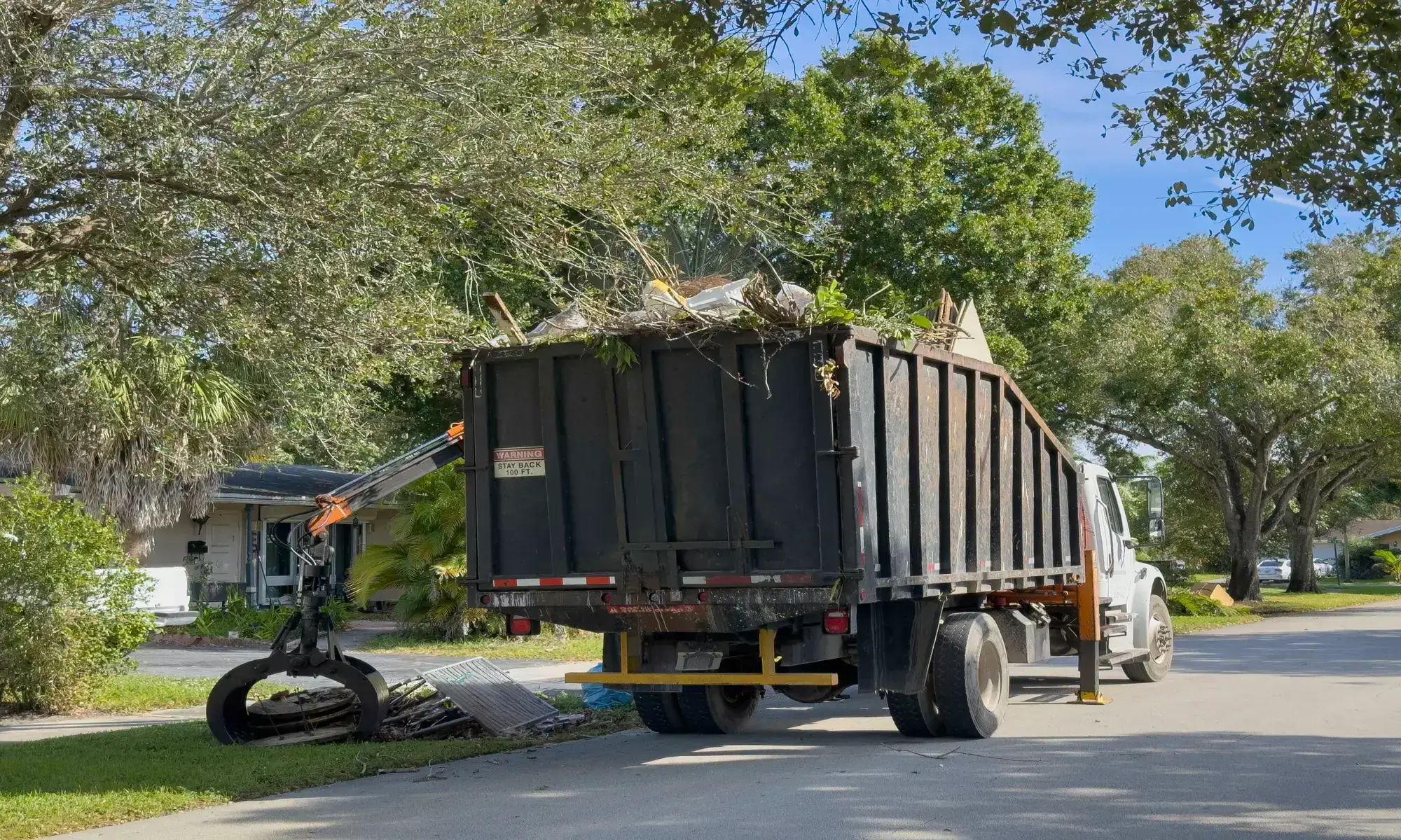 Garbage truck collecting yard waste on street.