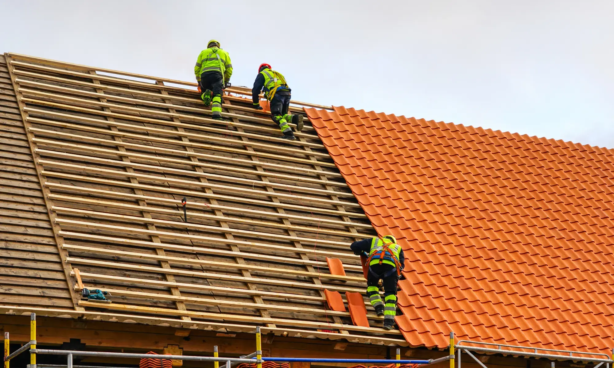 Workers installing tiles on a roof.