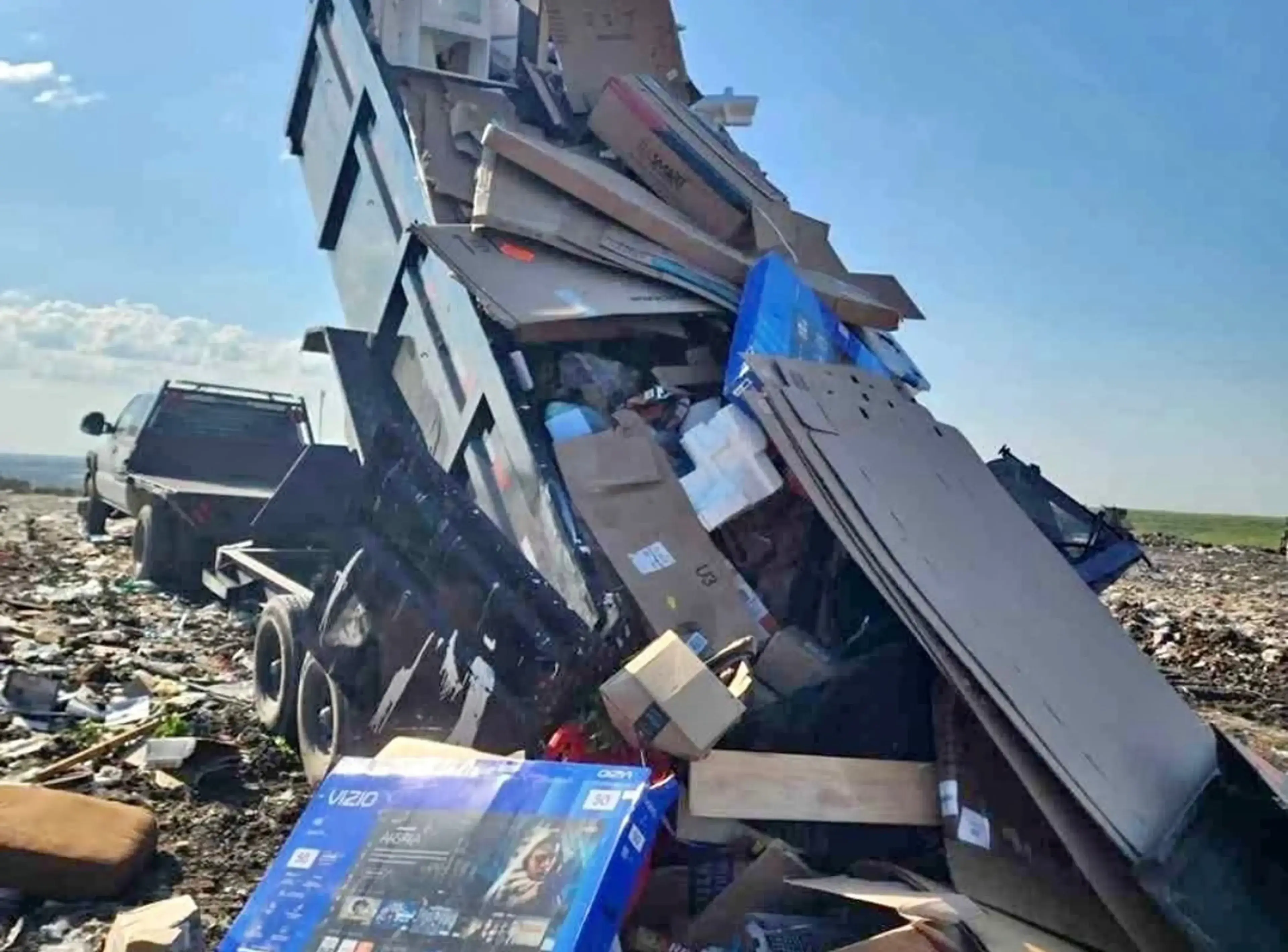 Truck unloading large pile of cardboard boxes.