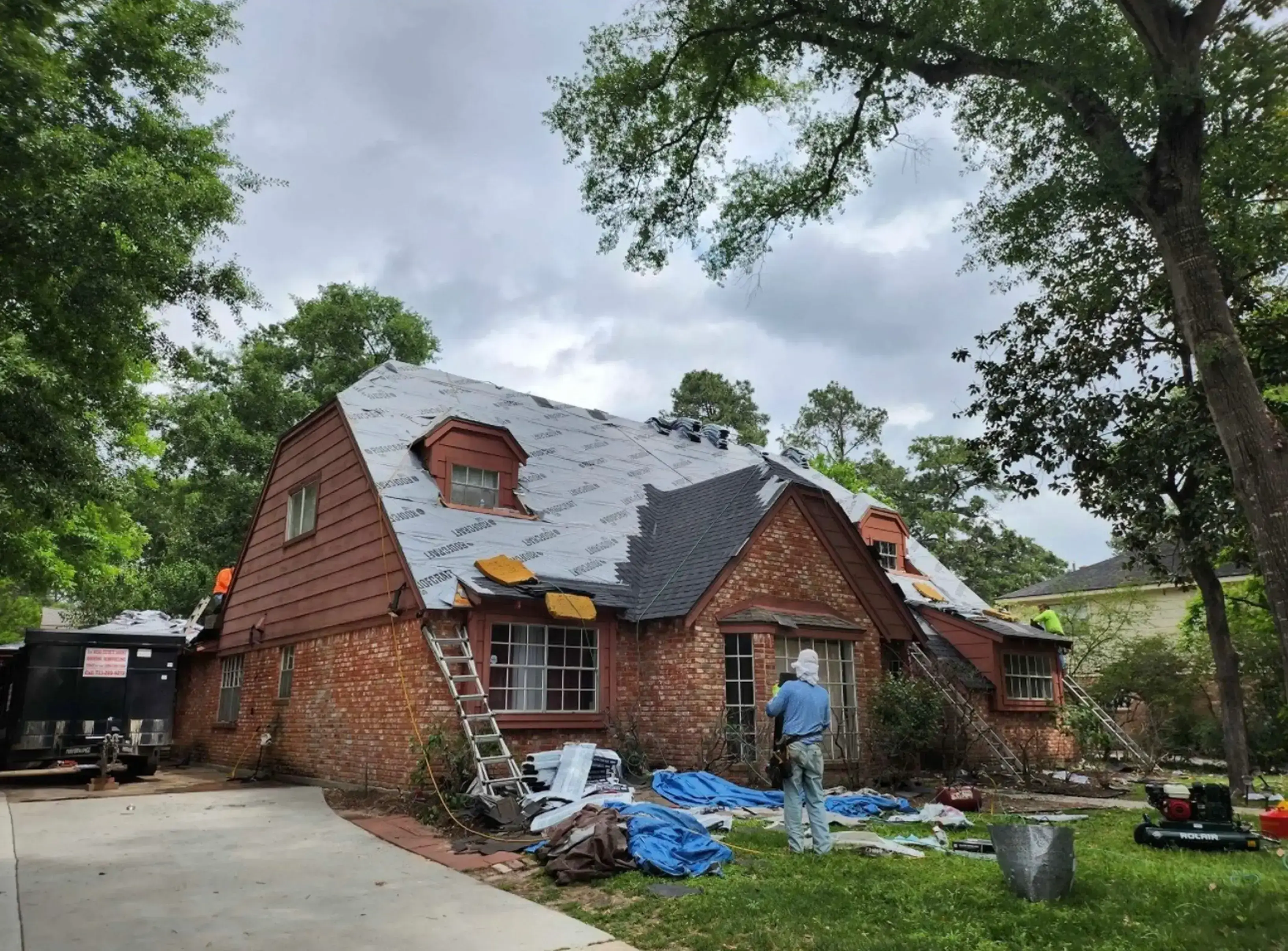 House under construction with workers on roof.