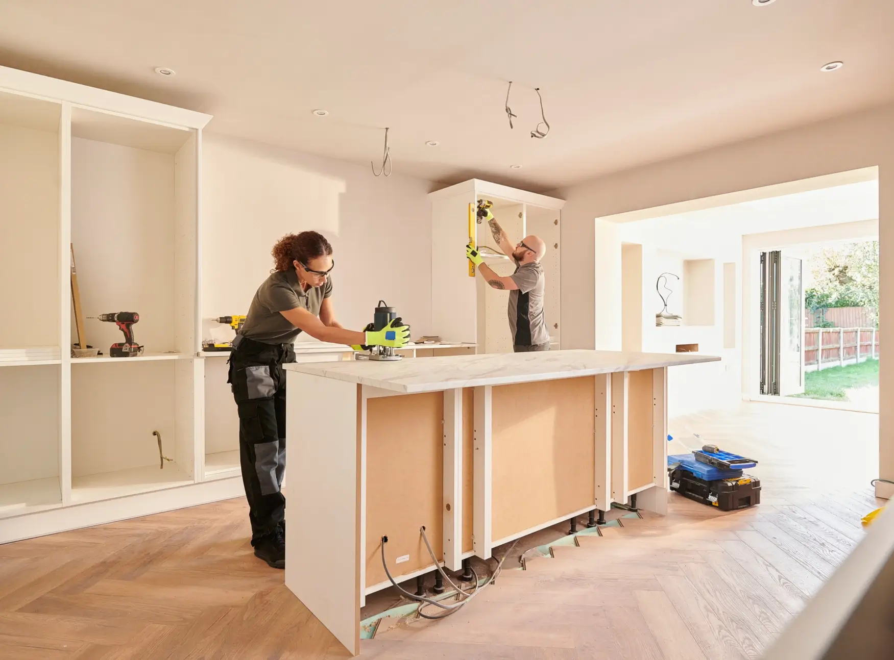 Worker renovating a modern kitchen by installing cabinets.