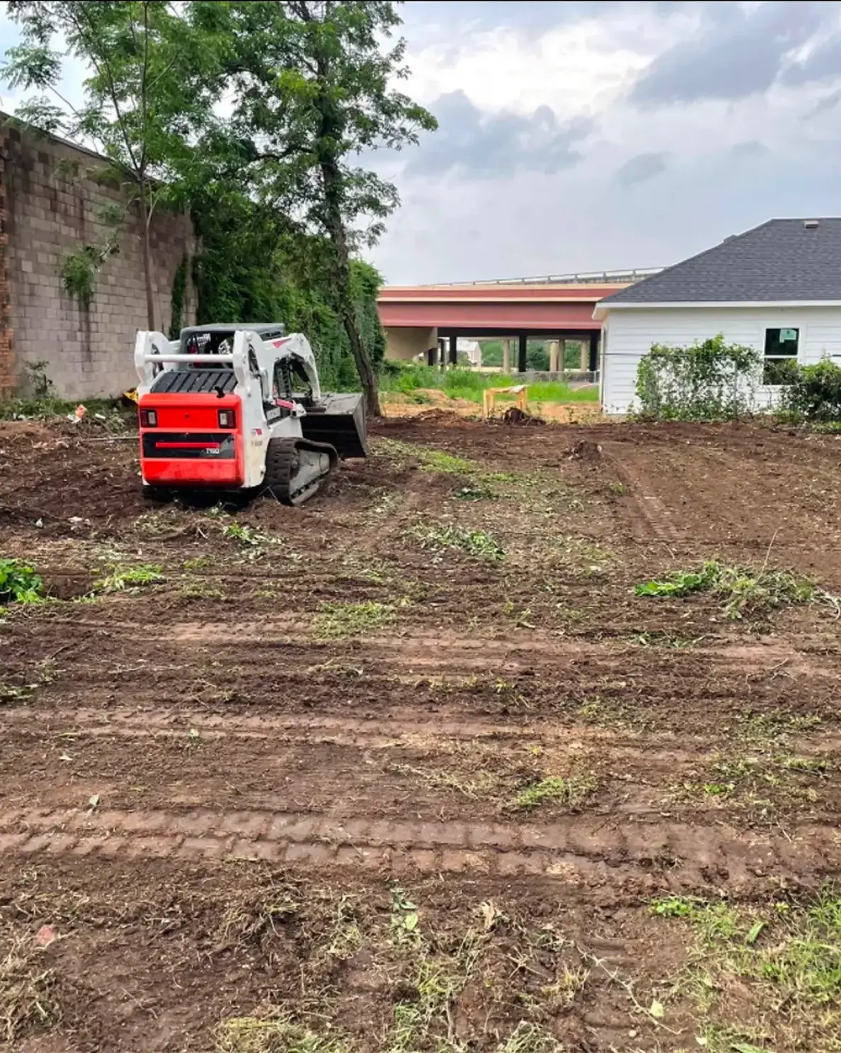Tractor leveling dirt near house and trees.