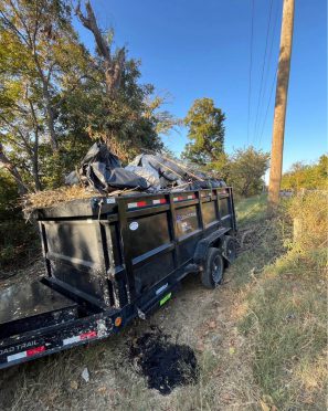 Trailer filled with debris on roadside.