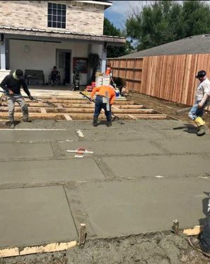 Workers laying concrete in a residential driveway.