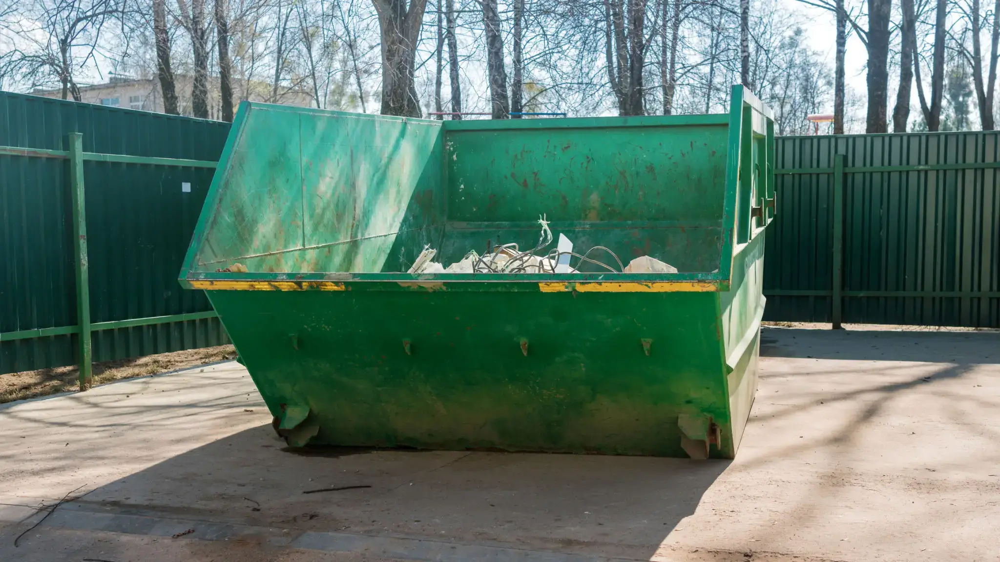 A large green dumpster filled with trash outdoors.