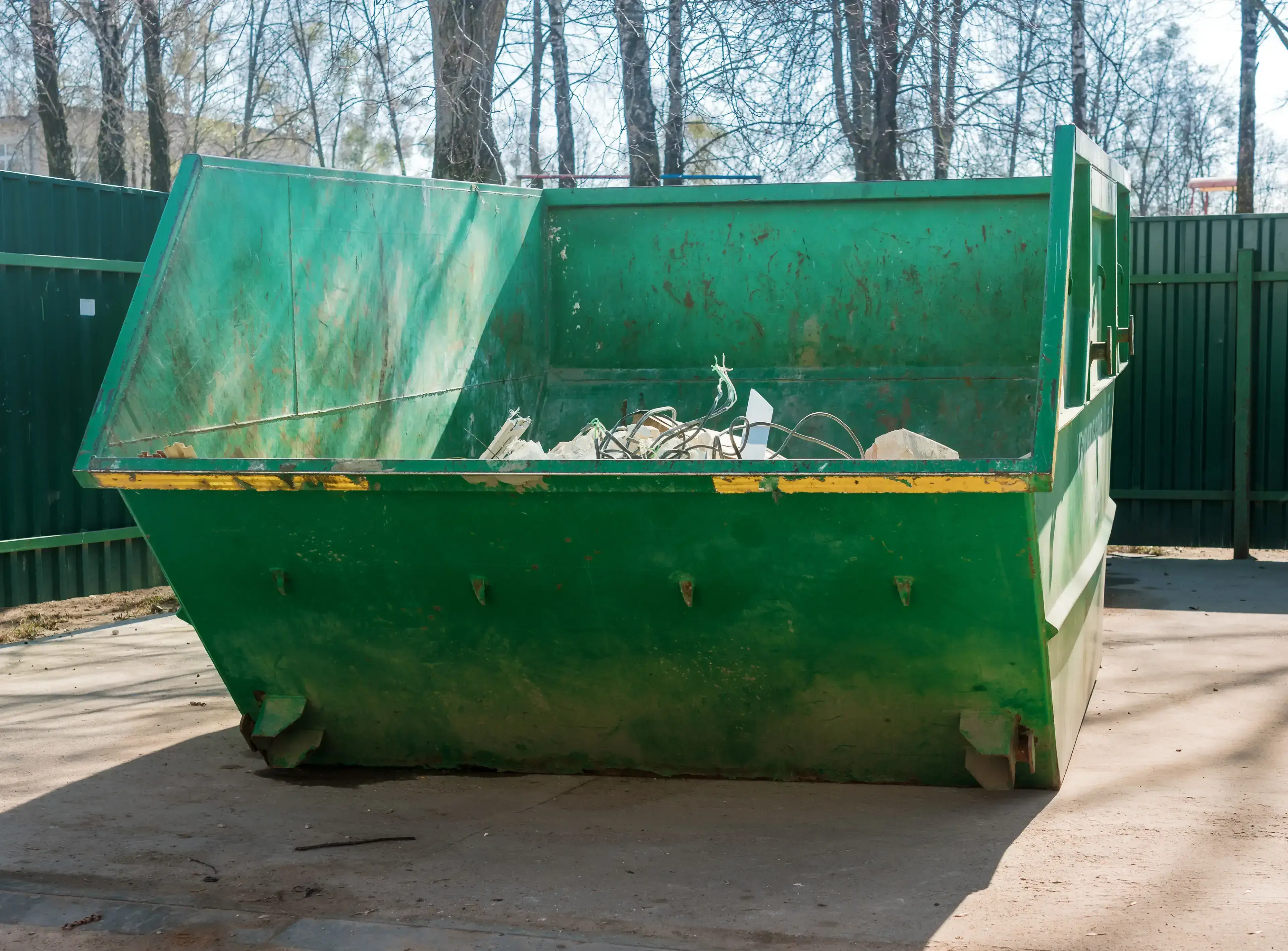 Large green dumpster filled with construction debris outdoors.