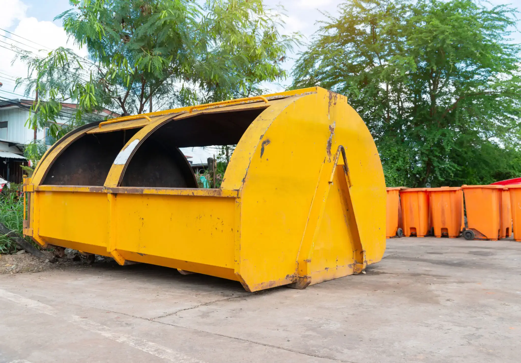 Large yellow industrial container outdoors with trees in background.