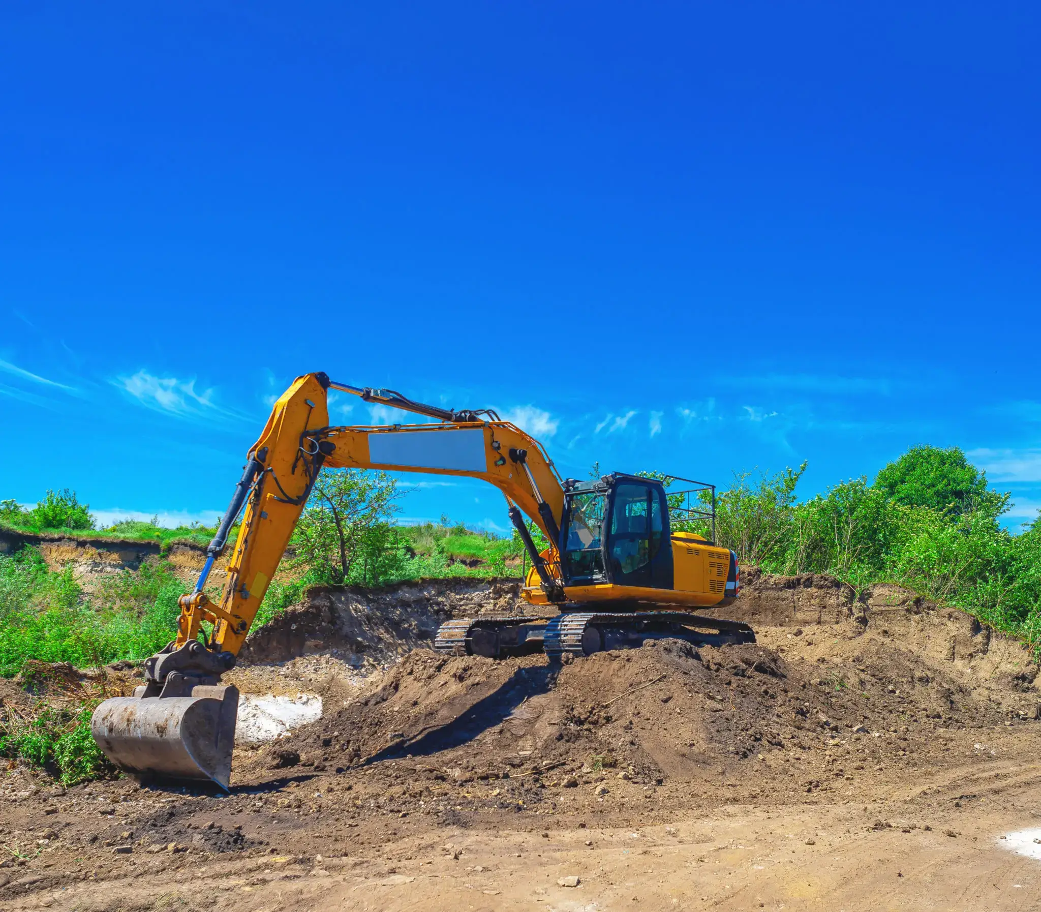 Excavator moving dirt under a clear blue sky.